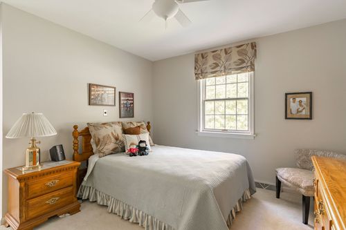 Bedroom with a wood headboard, floral window valance, and a matching nightstand