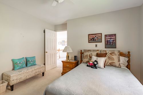Bedroom with turquoise accent pillows on a cushioned bench beside a wood four-poster bed