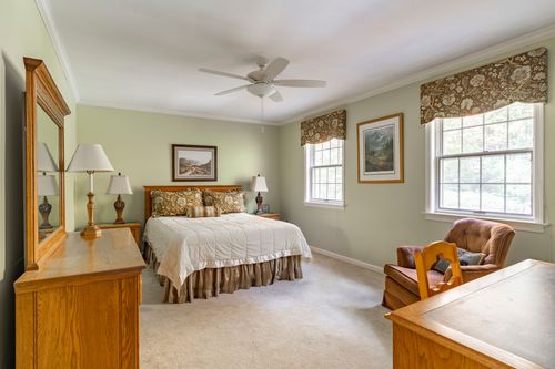 Sage-green bedroom with a wood bed frame, floral valances, and an oak dresser mirror