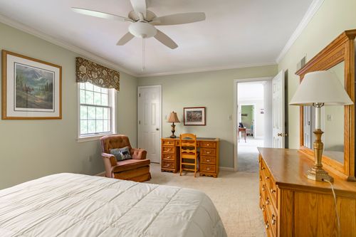 Bedroom with a leather recliner, oak desk, and framed mountain landscape art