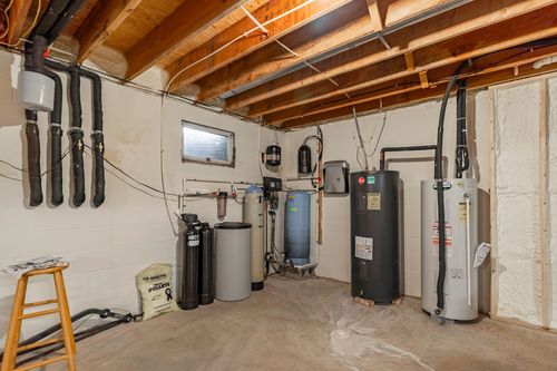 Unfinished basement mechanical room with a water heater, water softener, and utility sink