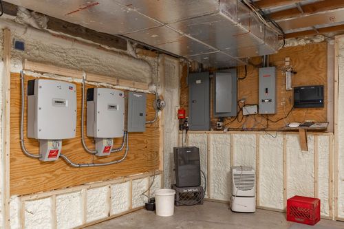 Basement utility room with solar inverters, electrical panels, and a dehumidifier