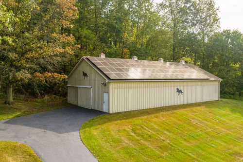 Aerial view of a large pole barn with solar roof panels and horse silhouette decals