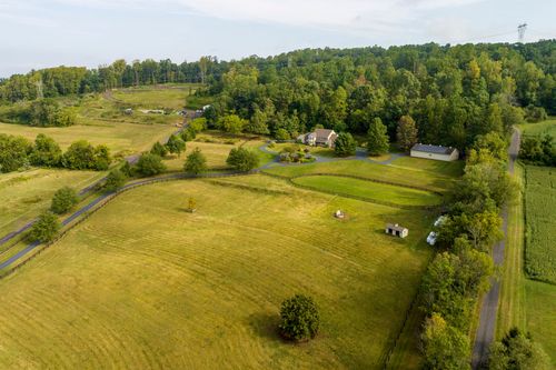 Aerial view of a country home with a curved driveway set among wooded acreage