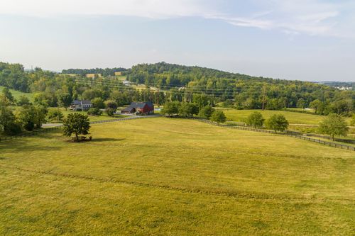 Aerial view of a red barn and farmhouse set among open pasture and fencing
