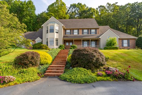 Two-story home with a bay window, covered porch and brick walkway lined with landscaping
