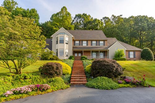 Two-story brick and shingle home with a brick step walkway through landscaped beds