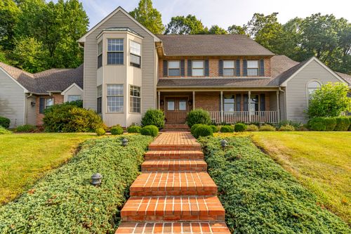 Front facade of a two-story home with a brick paver walkway and manicured shrubs