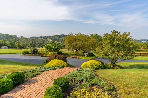 View from the front walkway across a paved driveway toward rolling countryside