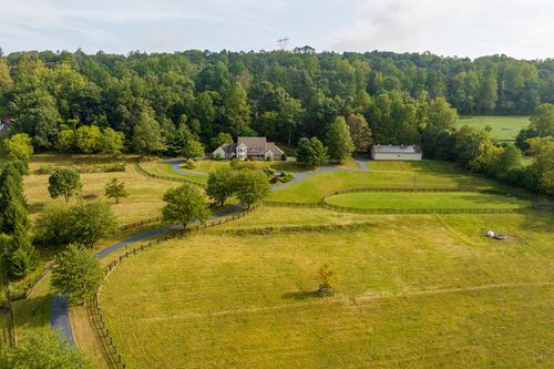 Aerial view of a country estate with a large fenced paddock and long driveway