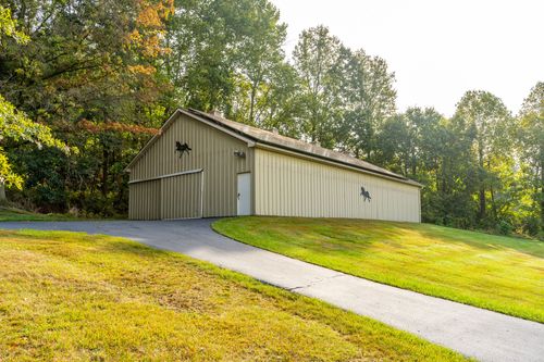Tan pole barn with horse silhouette decals set beside a paved driveway