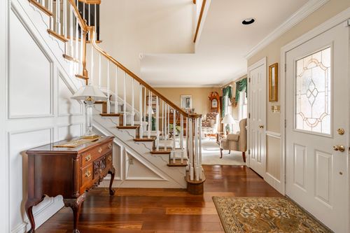 Front hall with a curved wood staircase, patterned runner rug, and rich hardwood flooring