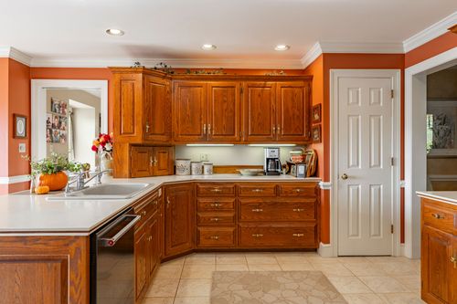 Kitchen with burnt-orange walls, honey oak cabinetry, and white countertops over tile flooring