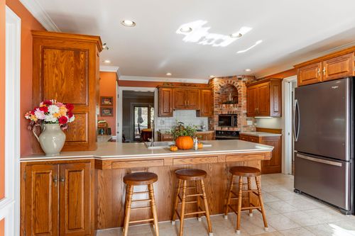 Kitchen island with wood stools, light countertops, and a brick chimney breast in the back corner