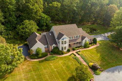 Aerial view of a brick and vinyl two-story home with a three-car garage and landscaped beds