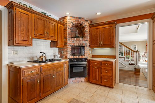 Kitchen with a brick arched niche over the black range, oak cabinets, and tile backsplash