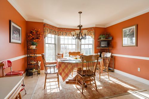 Orange dining nook with a plaid-topped table, bay window seating, and a wrought iron chandelier