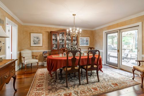 Formal dining room with a red-clothed table, cherry chairs, china cabinet, and French doors to the patio