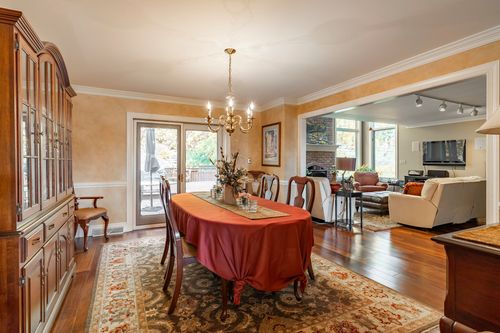 Dining room with a red tablecloth and chandelier opens to a family room with a brick fireplace