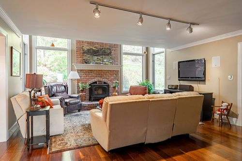 Family room with a brick fireplace, leather recliners, tan sectional sofa, and floor-to-ceiling windows