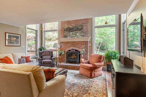 Family room with a brick fireplace, red patterned armchair, and a wall-mounted television