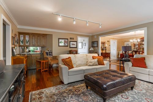 Open-concept family room with built-in shelving, cream sofas, and a leather ottoman