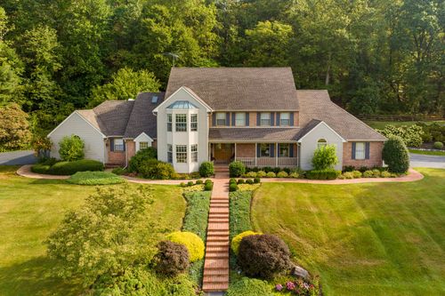 Aerial front view of a brick two-story home with a paved front walkway and lawn