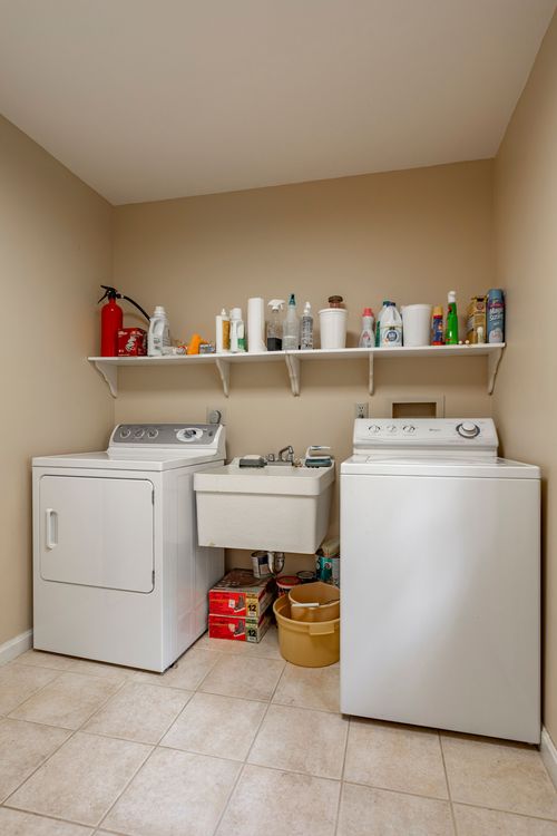 Laundry room with a white washer and dryer flanking a utility sink
