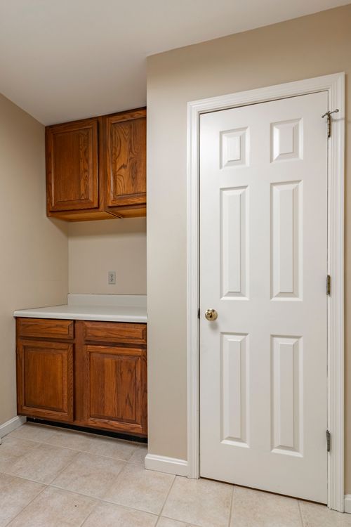 Mudroom nook with oak cabinetry, a laundry counter, and tile flooring