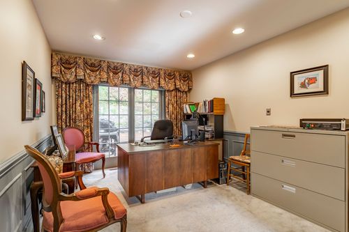 Home office with a cherry desk, floral drapery, and a glass door leading outside