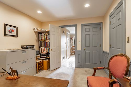 Home office with a bookshelf, gray file cabinets, and a red upholstered chair