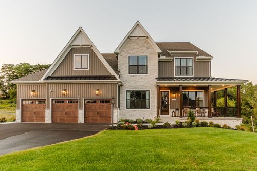 Modern farmhouse exterior with board-and-batten siding, stone accents, and a three-car garage
