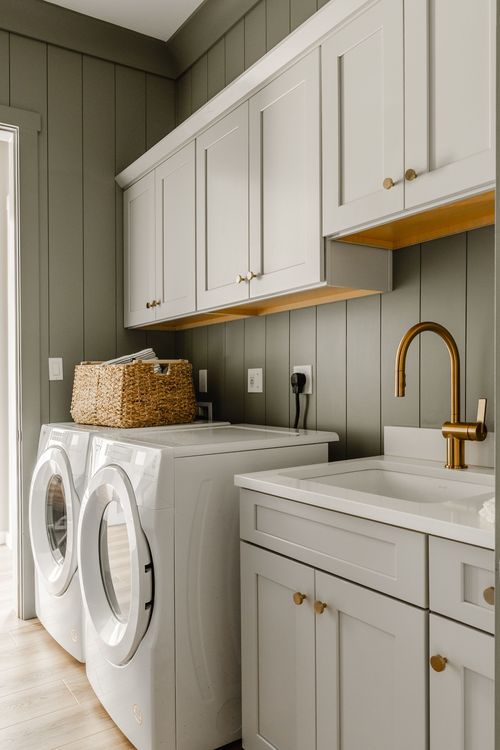 Laundry room in Lititz, PA with sage cabinetry, brass faucet and a white washer and dryer