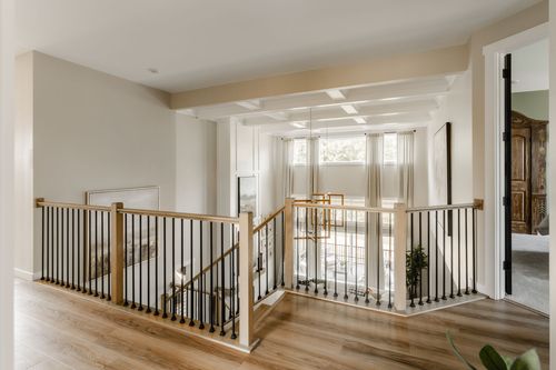 Loft landing with black metal railing, a coffered ceiling and a large window