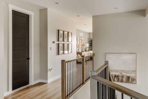 Upstairs hallway with a dark paneled door, gallery wall and wood stair railing