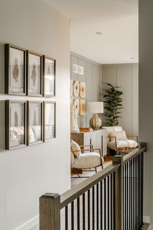 Sitting nook with a gallery of framed prints, cream chairs and a wood side table
