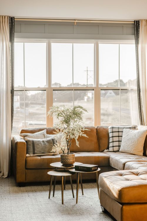 Living room with a leather sectional, layered nesting tables and a large picture window