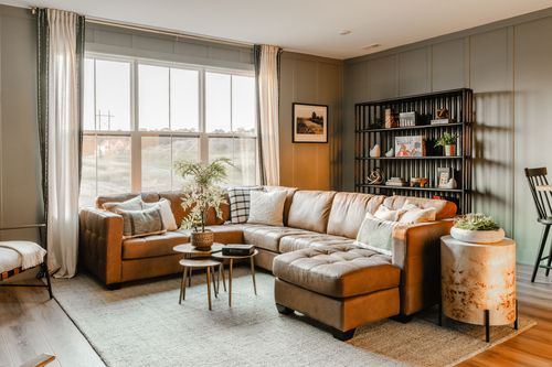 Living room in Lititz, PA with a tan leather sectional, bookshelf and accent chair