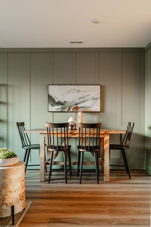 Dining table styled with dried florals and a wood block puzzle beneath abstract art