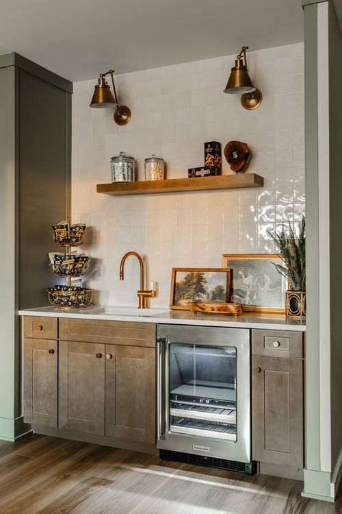 Wet bar with brass sconces, open wood shelving, wine fridge and stone counters