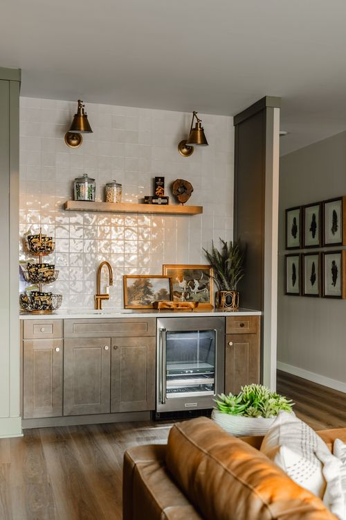 Wet bar with brass sconces, a glass-front wine fridge and a leather sofa nearby