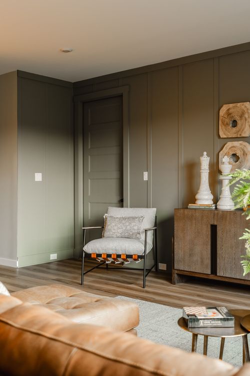 Sitting room with olive paneled walls, a dark door, chess piece decor and wood cabinet
