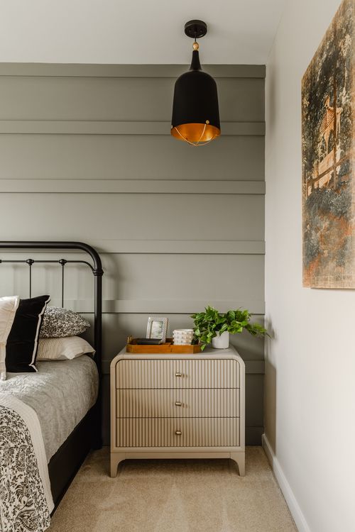 Bedroom with a black pendant light, iron bed frame and fluted nightstand