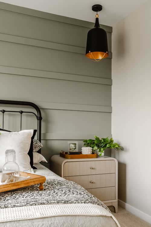 Bedroom close-up with a black pendant light, iron bed frame and styled nightstand tray