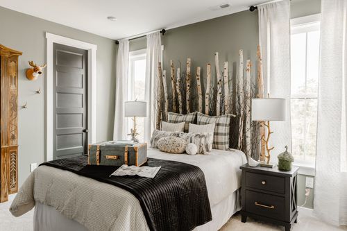 Bedroom with a birch-branch headboard, black bedding, dark door and mounted deer decor