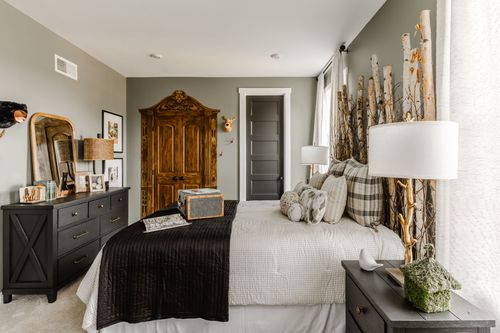 Bedroom with an antique carved wood armoire, birch-branch headboard and black dresser
