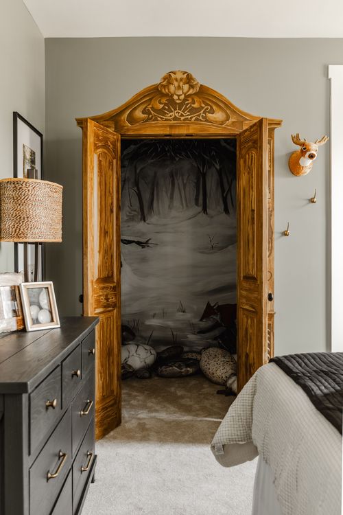 Ornate carved wood armoire opened to reveal a painted forest mural inside