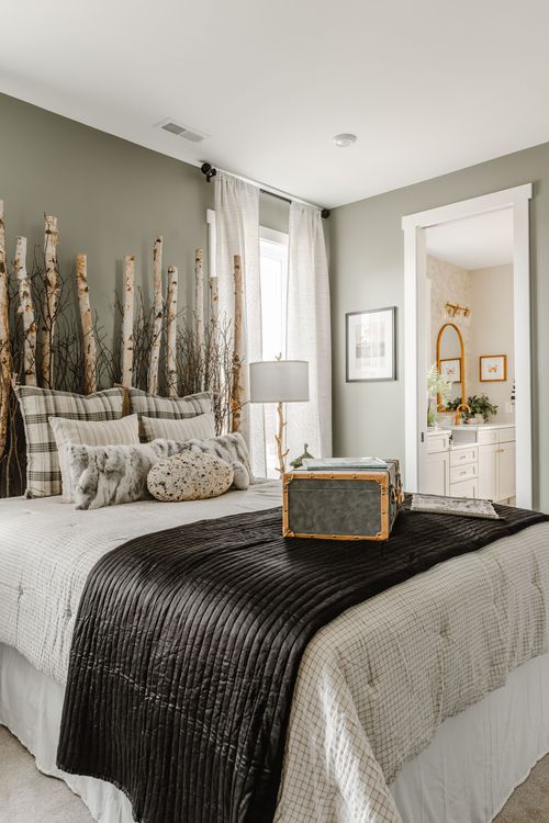 Bedroom with a birch-branch headboard, black quilted throw and a doorway to an en-suite bath