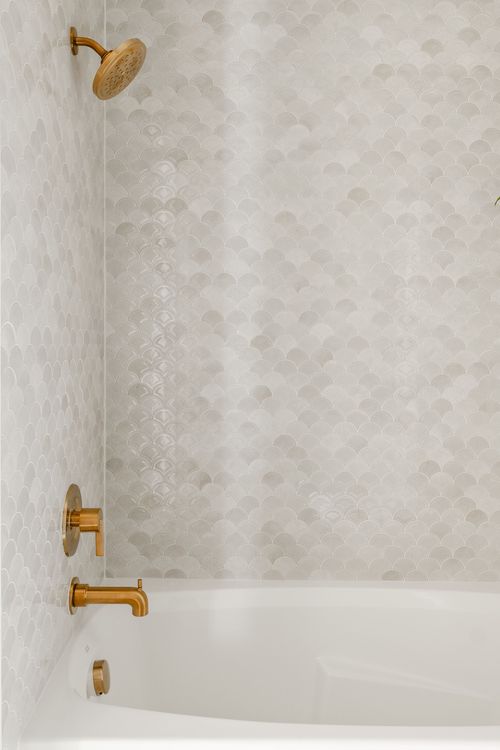 Tub-shower combo with scalloped tile walls and brass fixtures