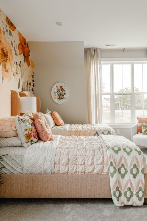 Kids' bedroom with a peach upholstered headboard, floral wallpaper mural and bay window